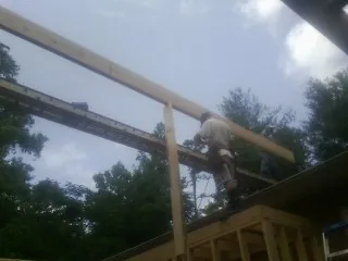 Carpenter setting a ridge beam over a new addition frame — Ice Dam Removal by Roofing Brothers in Uehling