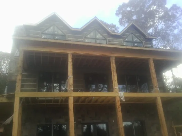 Dormers and porch framing on a large log home under construction — Roof Coating work by our crew in Uehling