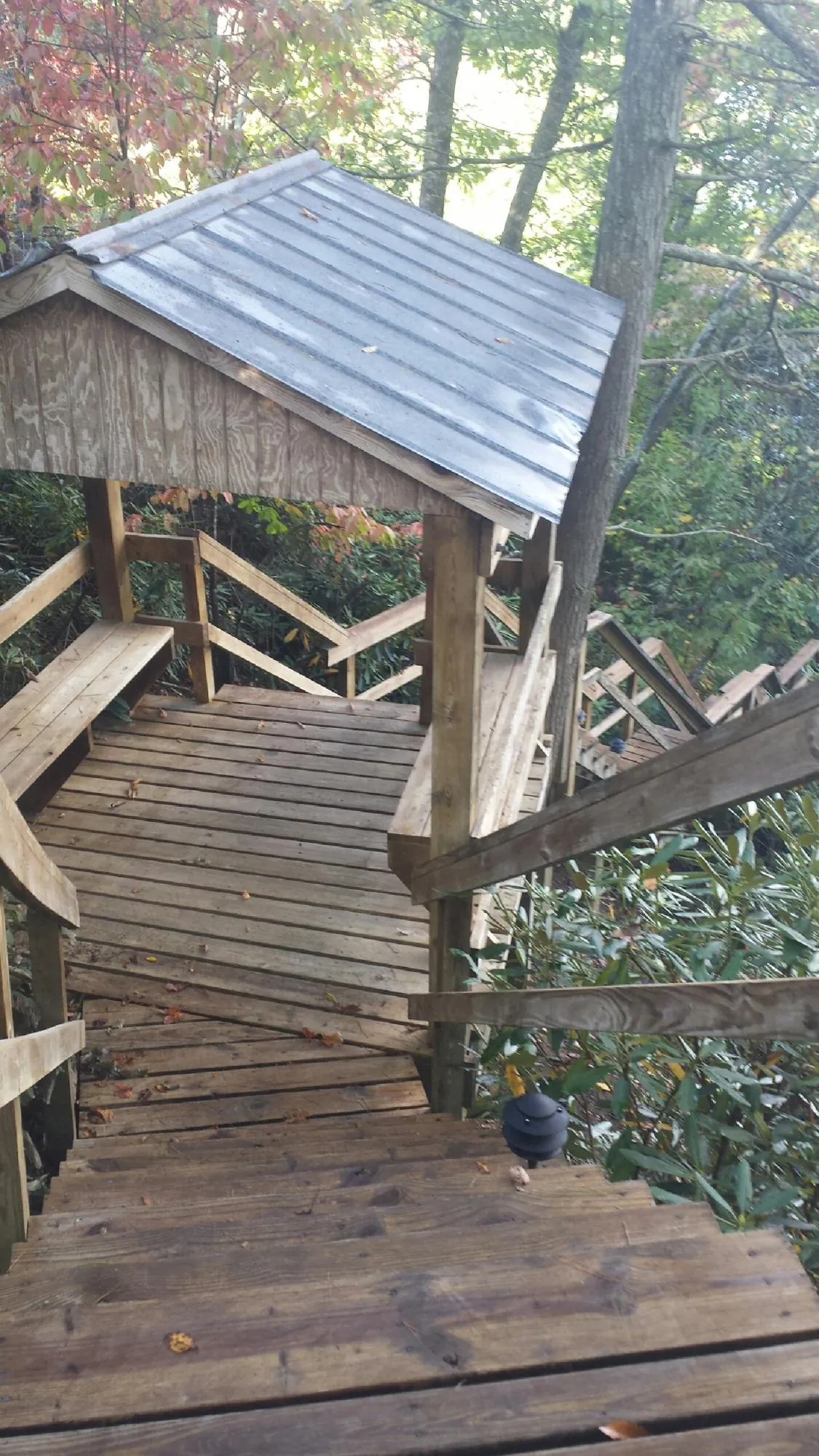 Metal roofed shelter over wooden steps on a wooded walkway — Skylight Repair & Installation work by our crew in Uehling