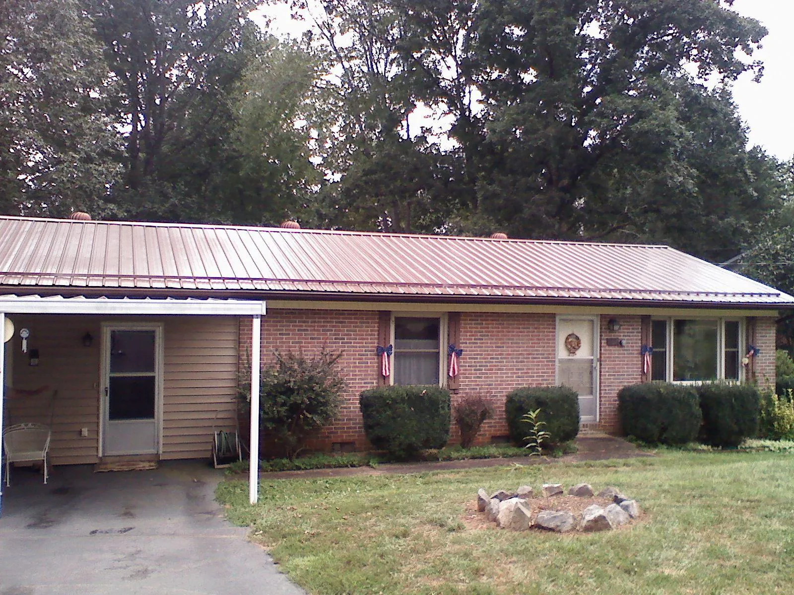 Bronze metal roof and carport on a brick ranch home — Roof Repair work by our crew in Uehling